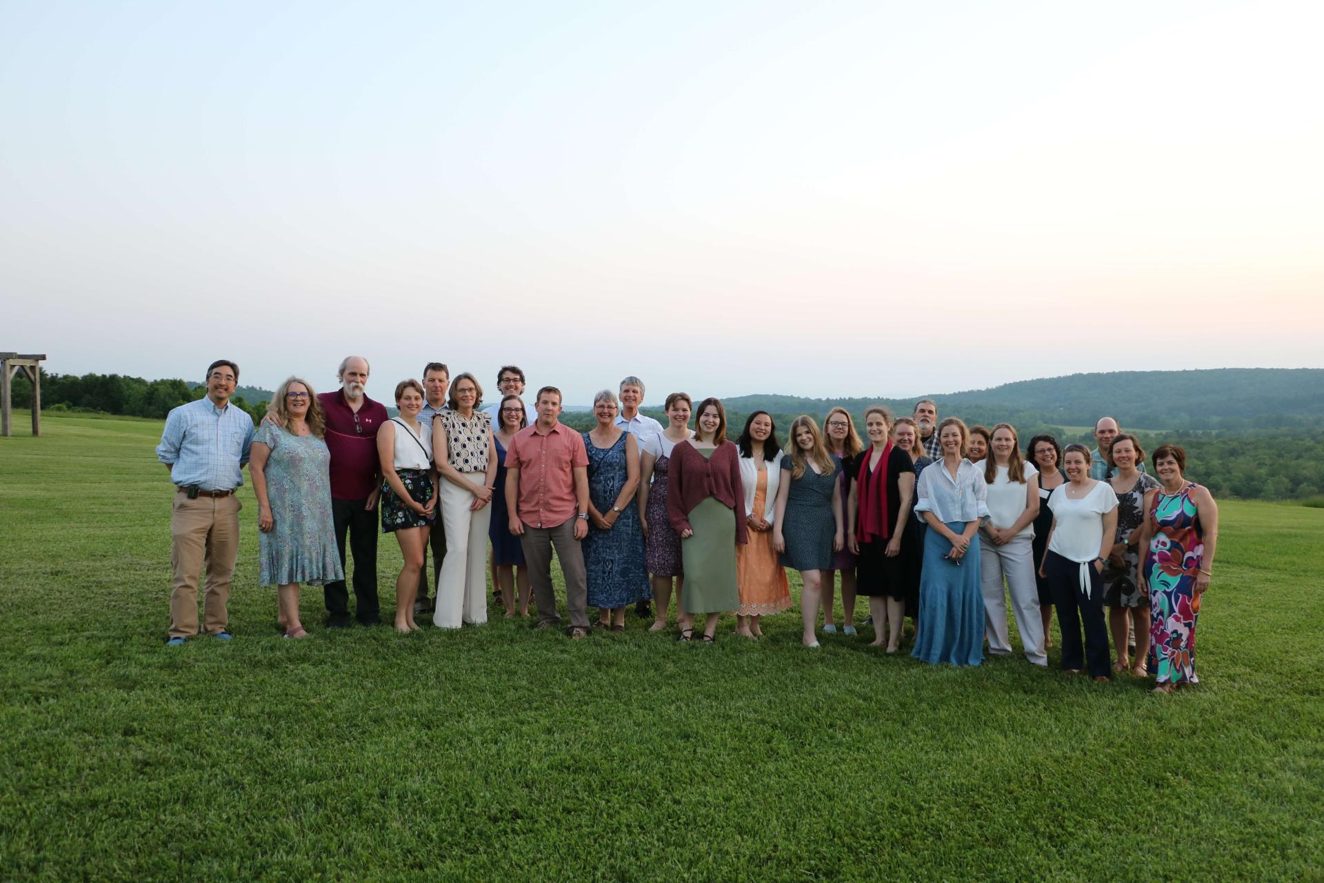 Members of the Vaccine Testing Center stand for a group photo in a field at dusk