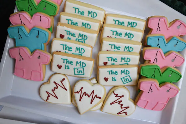Platter of frosted cookies in the shape of hearts, nametags, and scrub shirts.