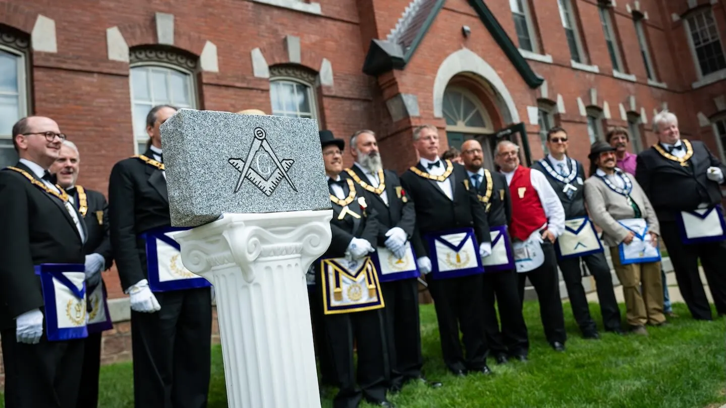 group of people gathered behind ceremonial granite cornerstone