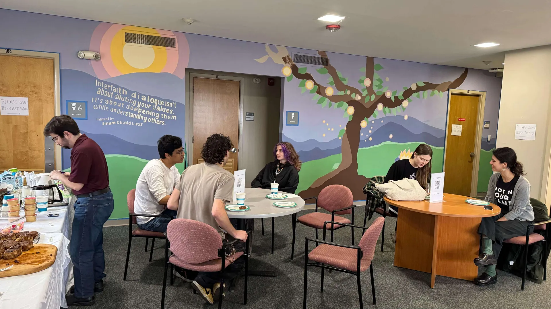 groups of student eating breakfast and there is a mural in the background
