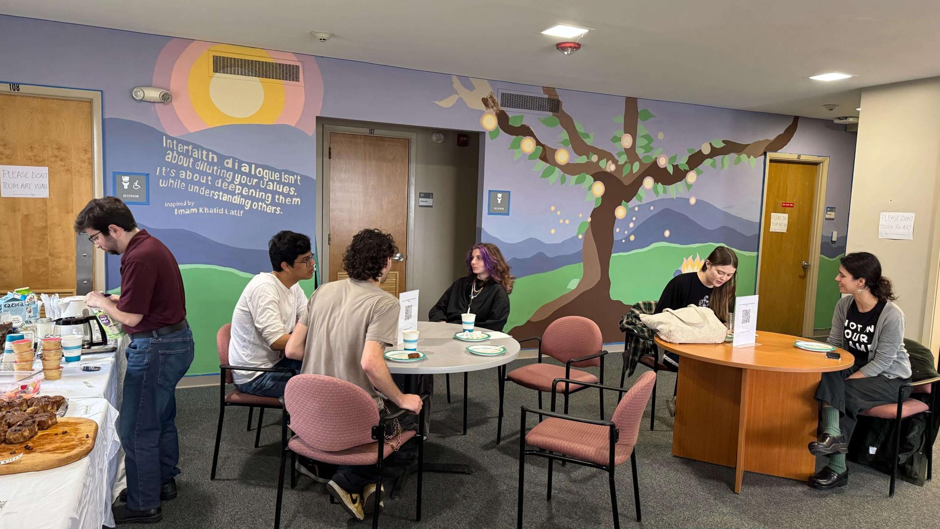 groups of student eating breakfast and there is a mural in the background