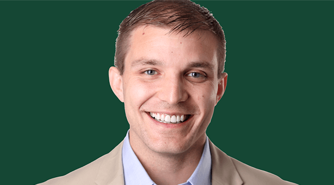 a man smiling, against a green background