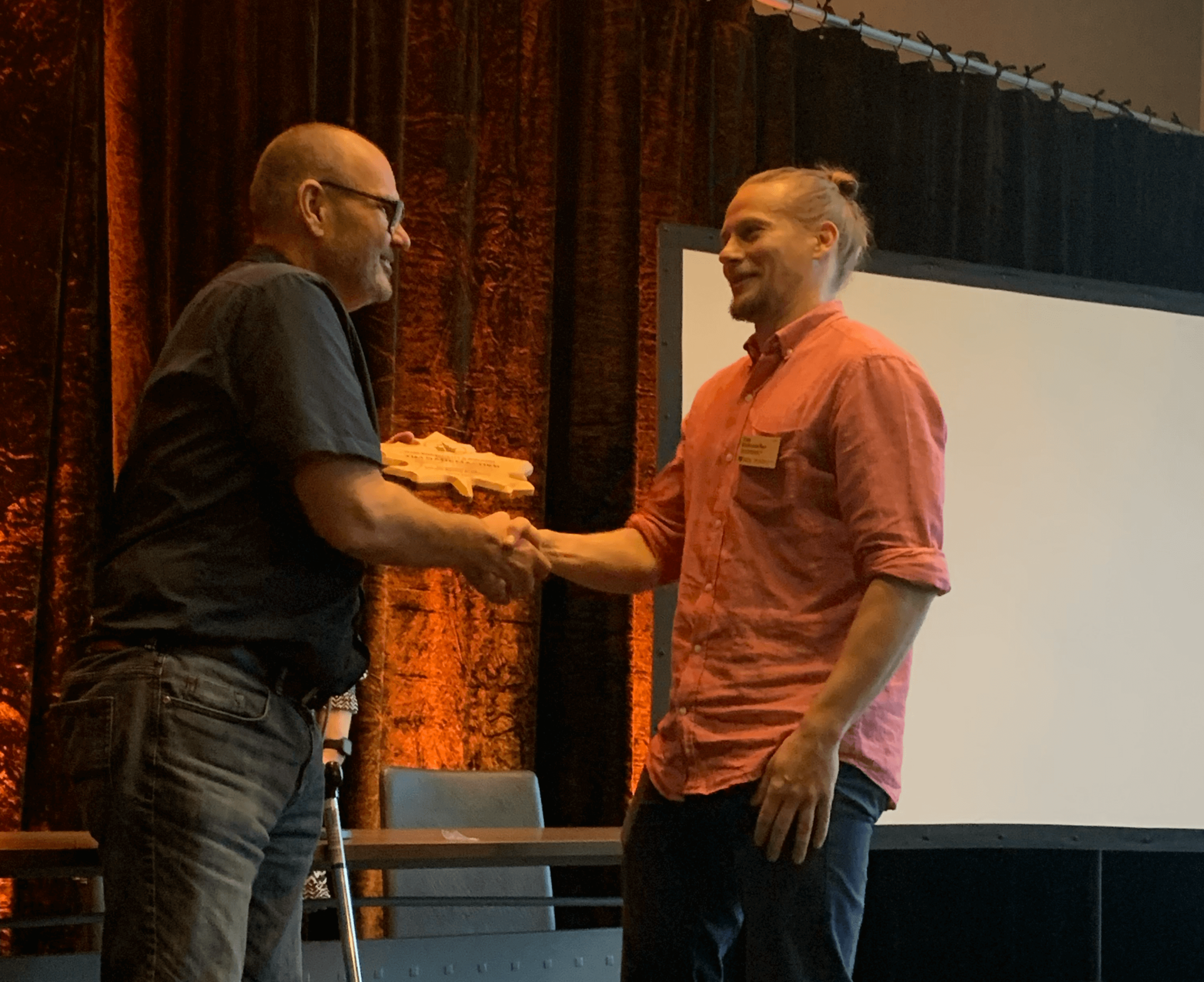 A man receiving an award from another man onstage