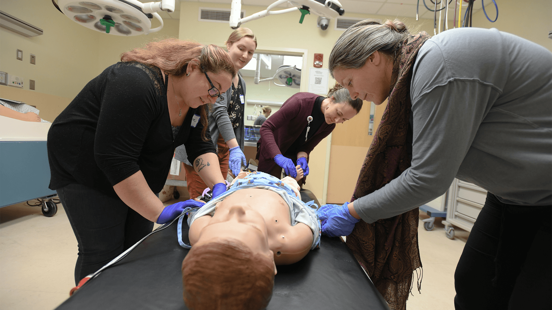 4 women practicing clinical skills on a manikin