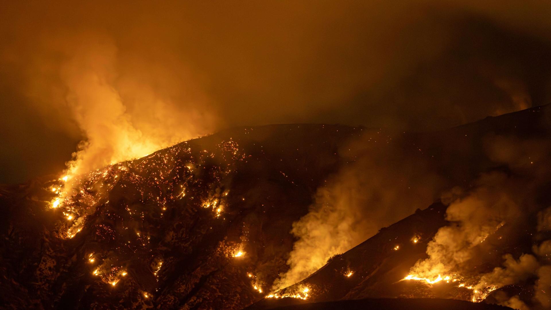a forest on a hillside is on fire at night