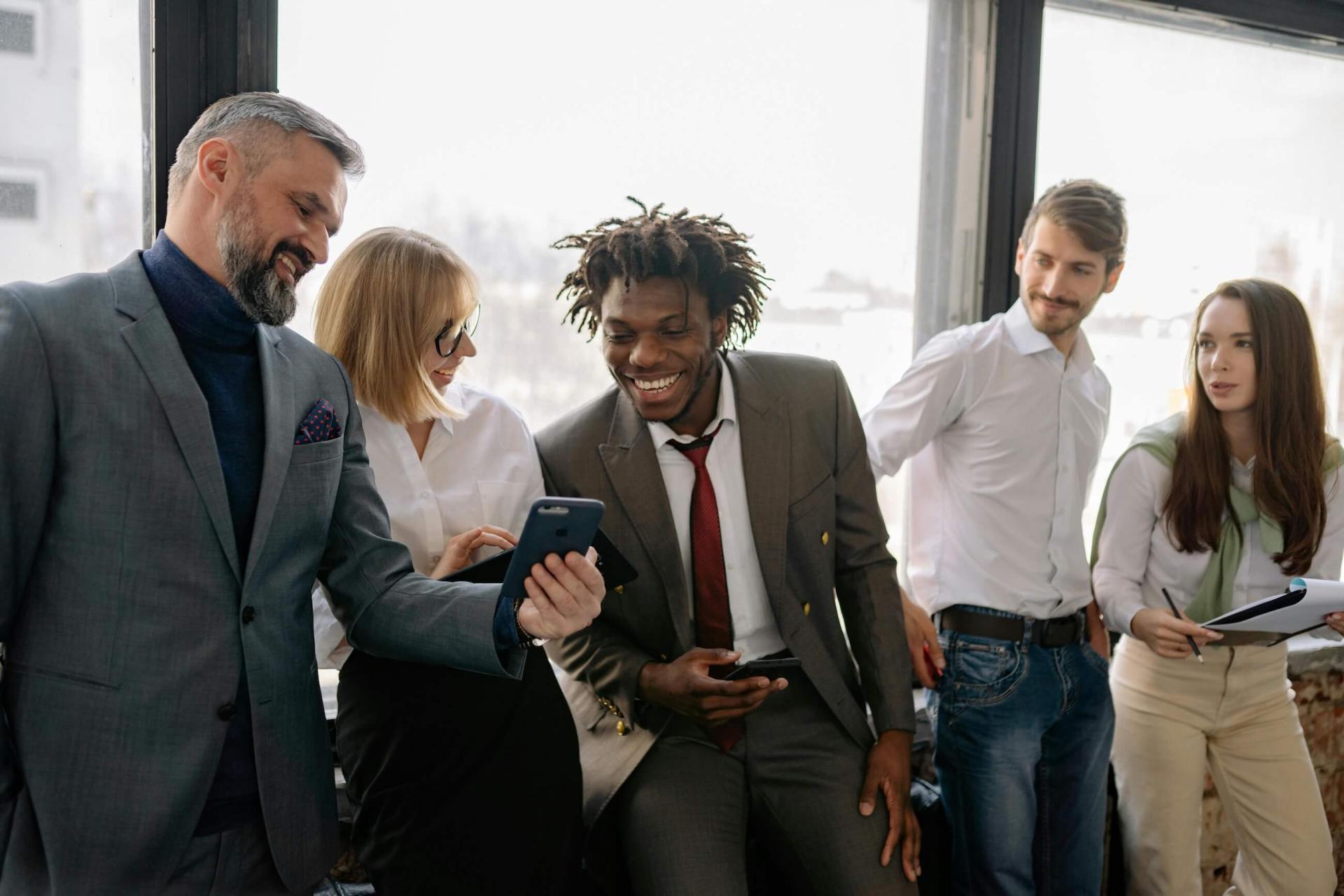 five business casual people laughing in an office