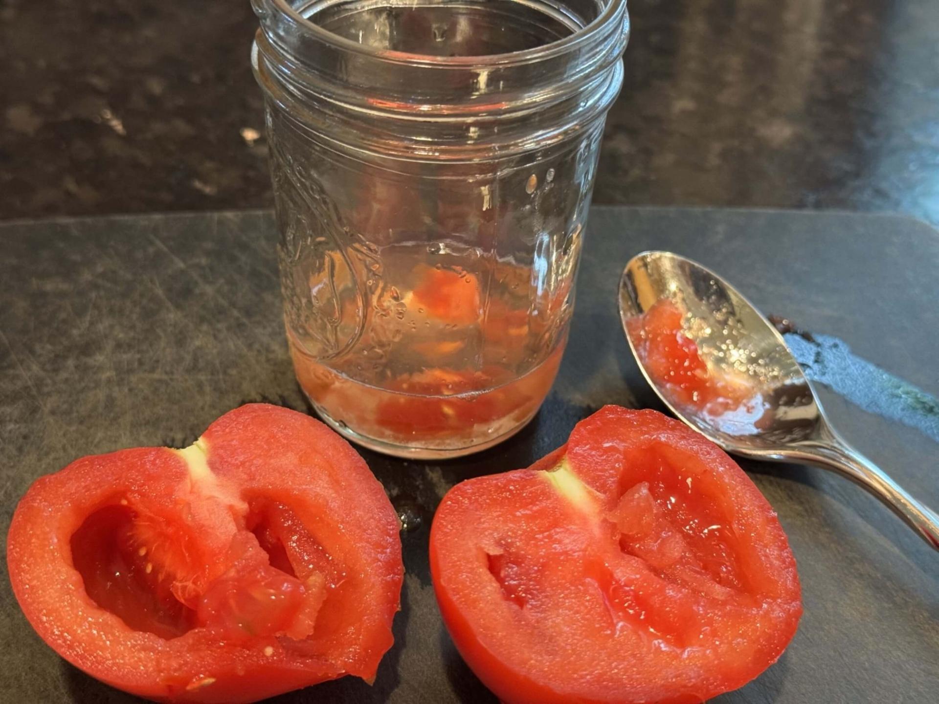 a halved tomato with seeds in a jar