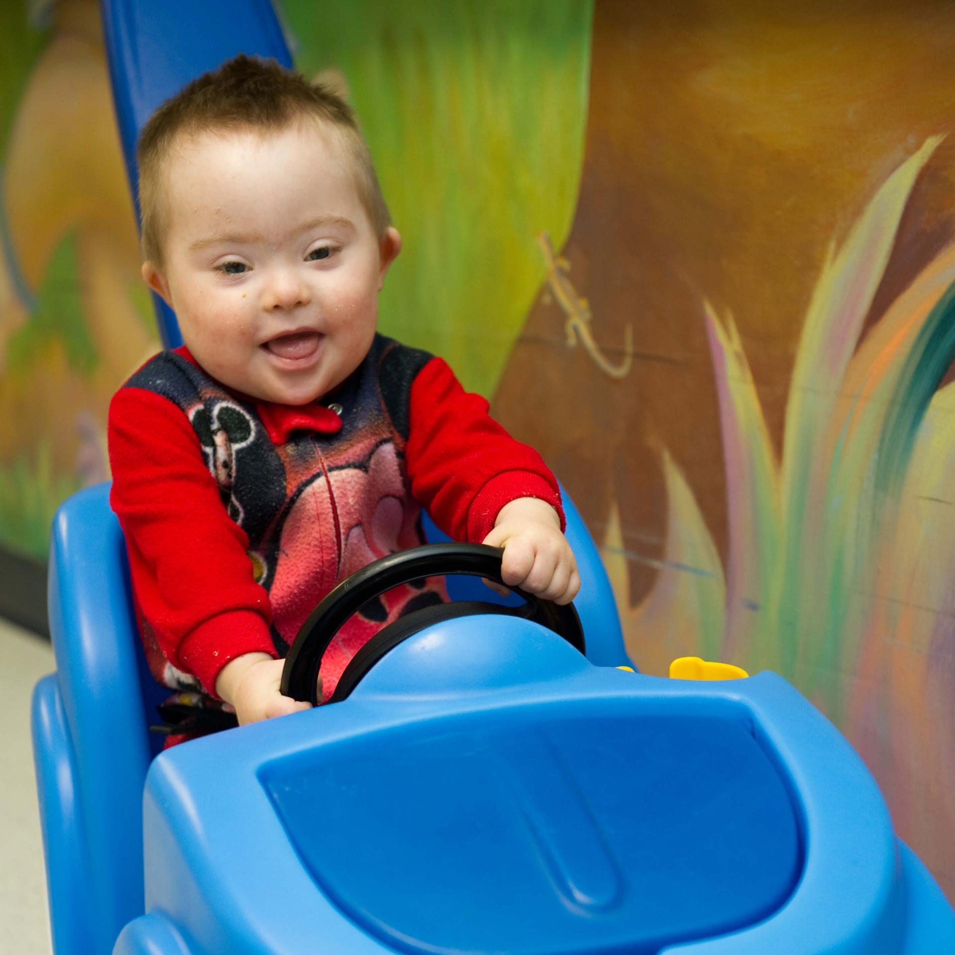 toddler driving a toy car