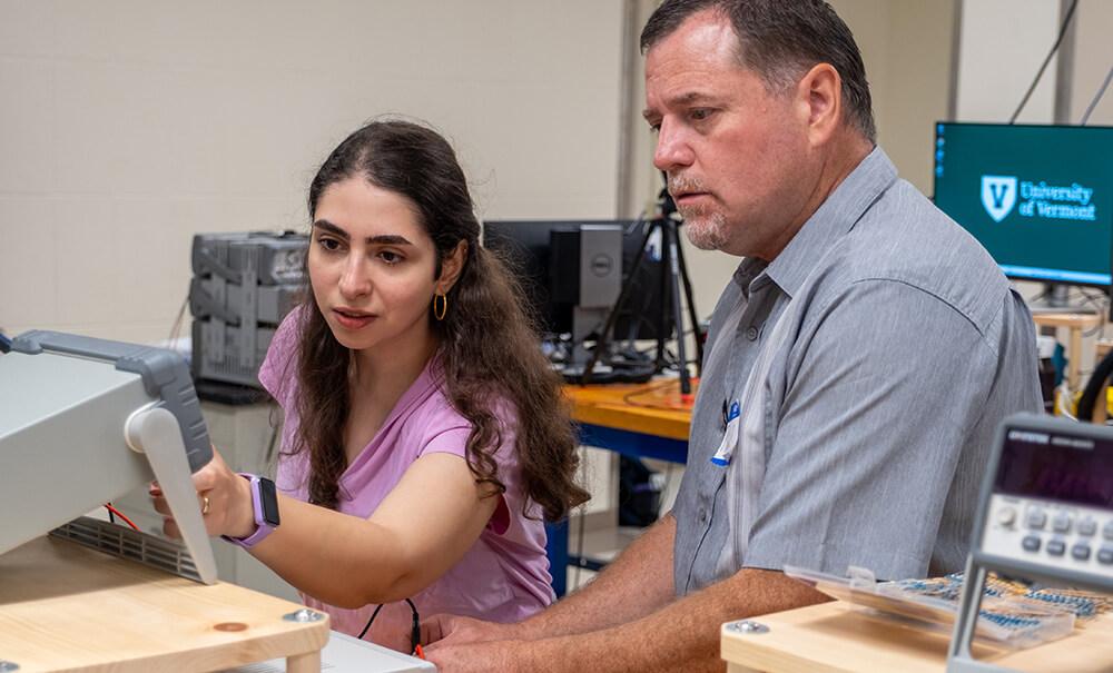 Electrical Engineering Ph.D. student and a research assistant Parmida Amngostar assists St Albans School System technology consultant Philip Gervais with building a circuit board