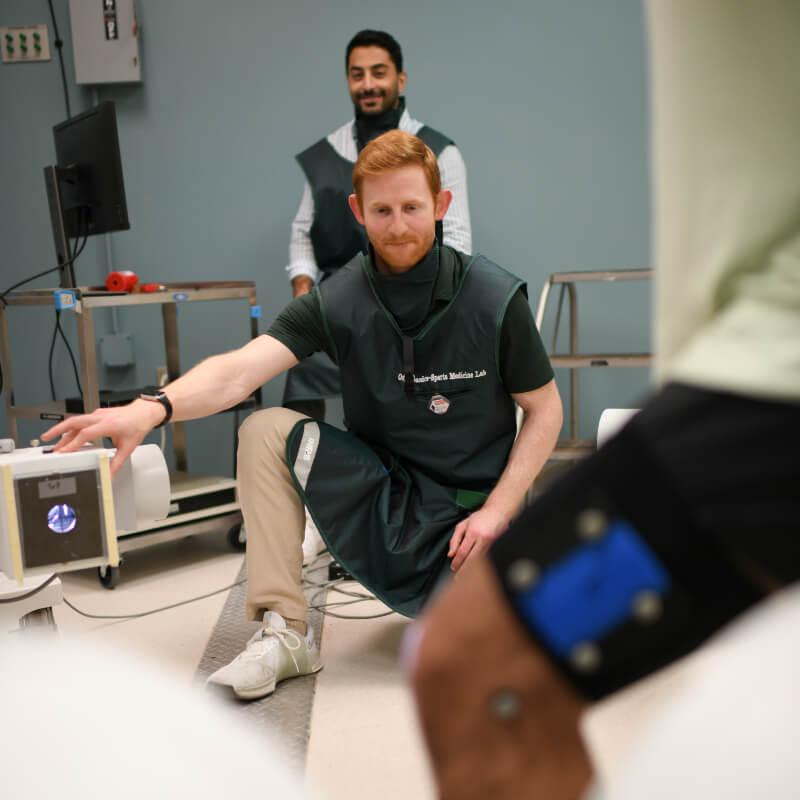 two people in protective aprons do imaging of a persons knee