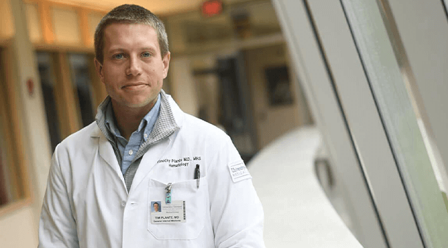 a man in a white coat smiling