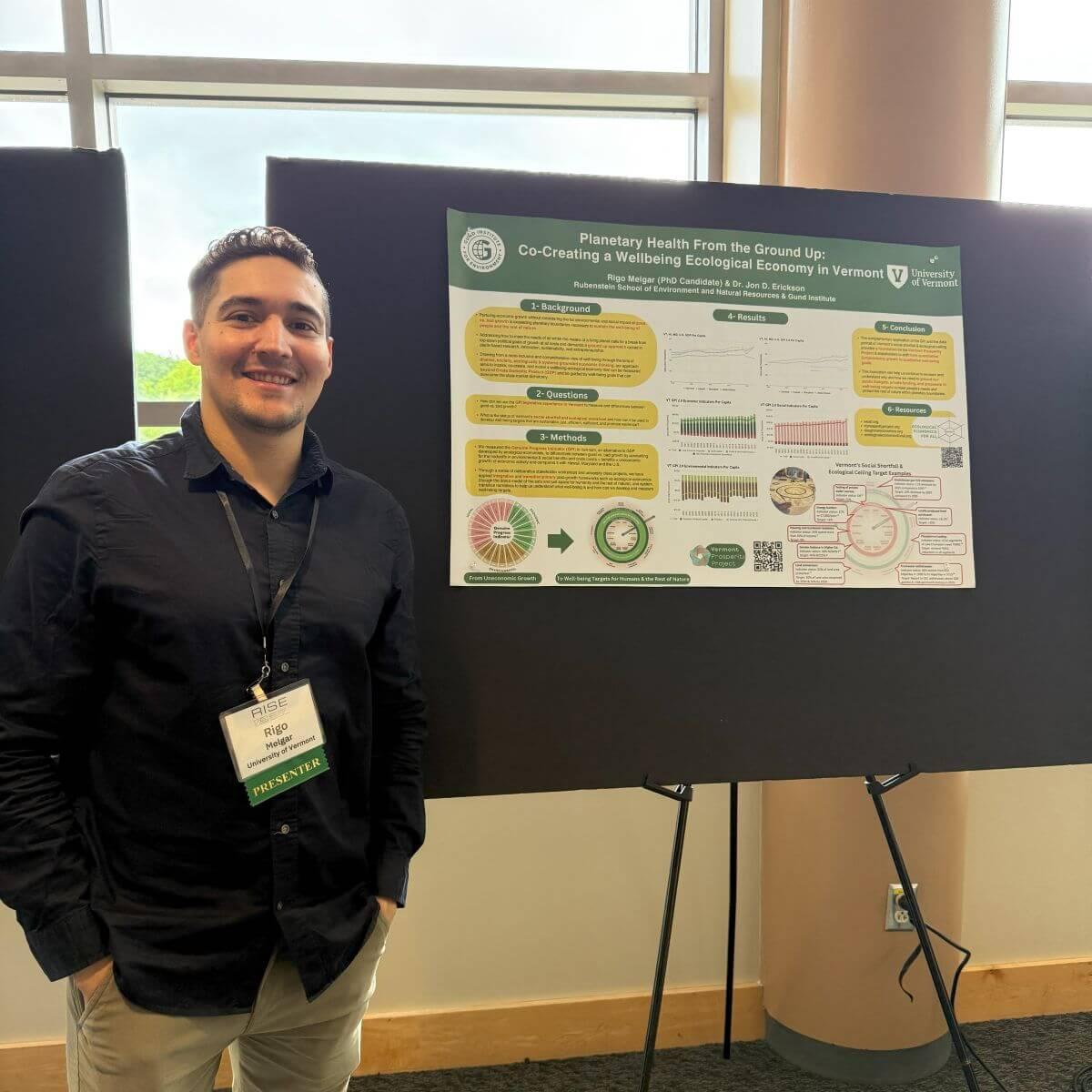 Rigo Melgar, Ph.D. student, standing next to a research poster.