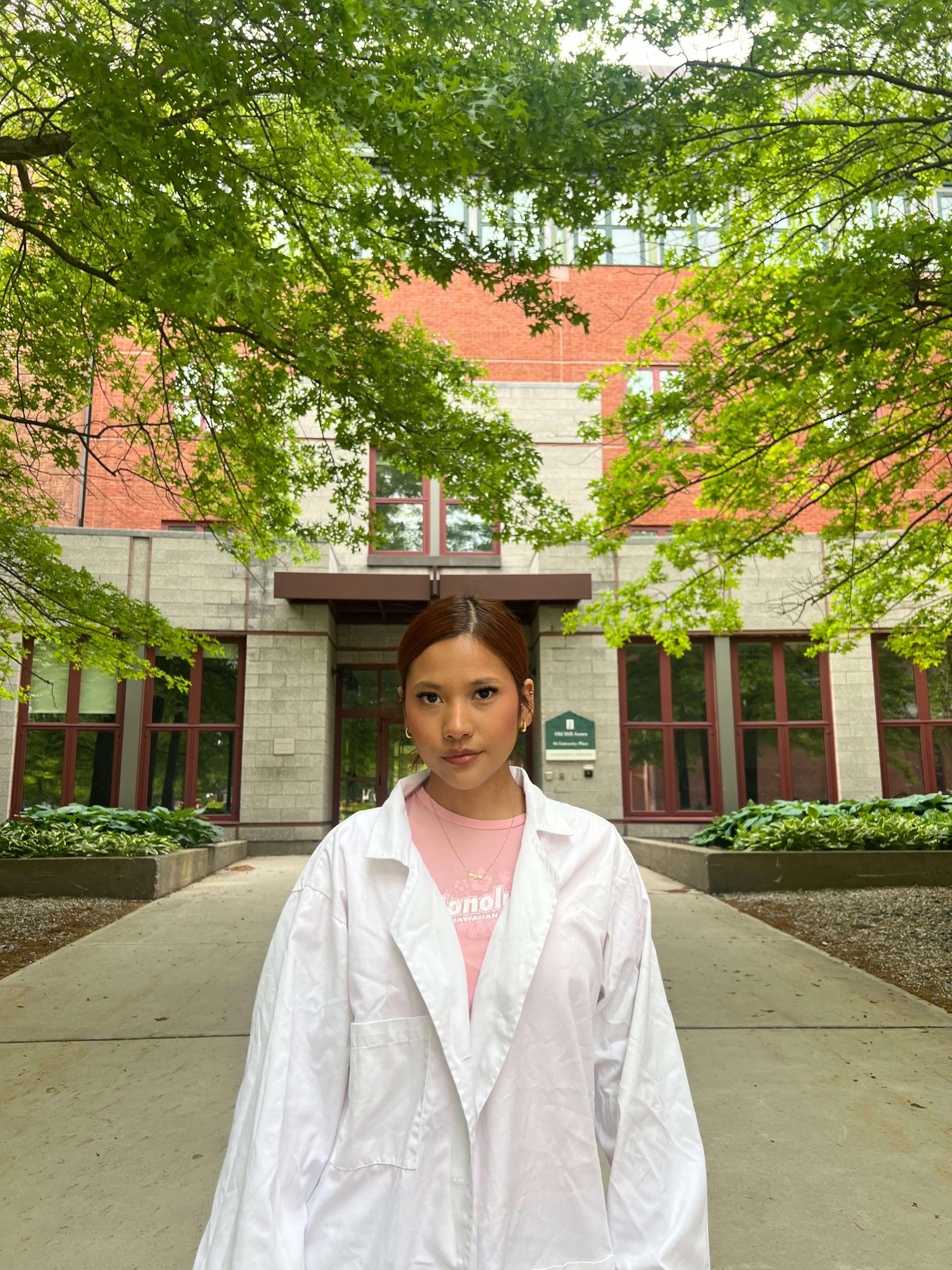 Student in a lab coat on a college campus