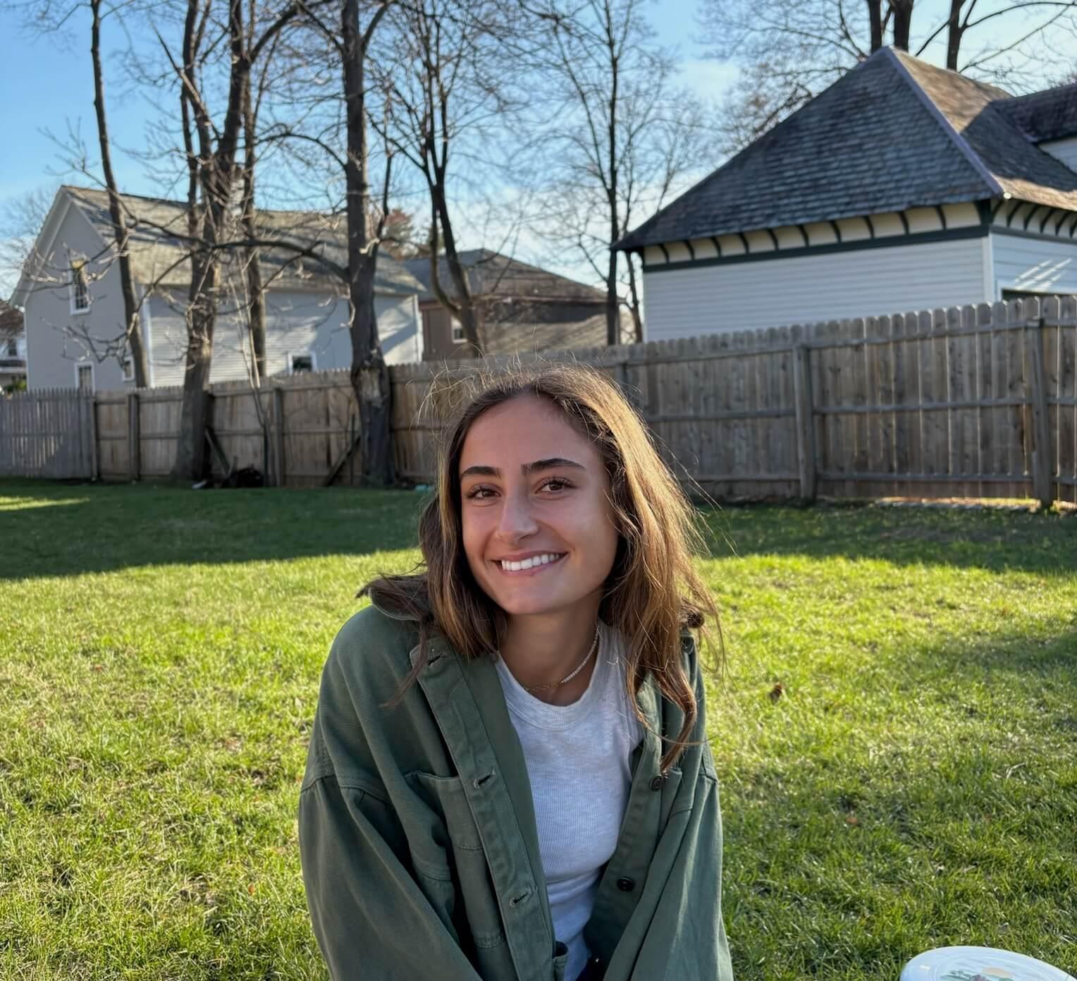smiling person sitting on lawn on a sunny fall day