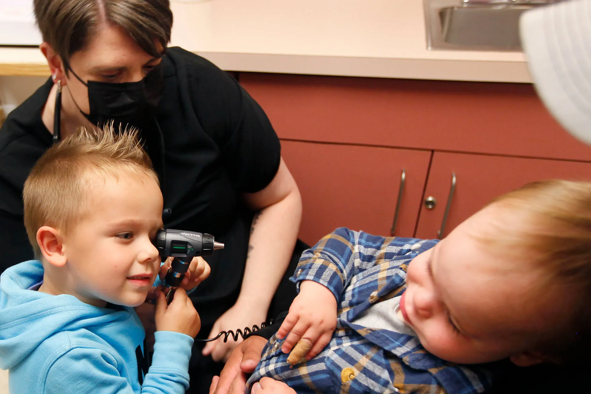 child using doctors scope to look at toddler