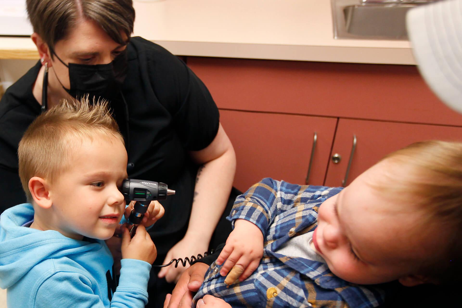 child using doctors scope to look at toddler