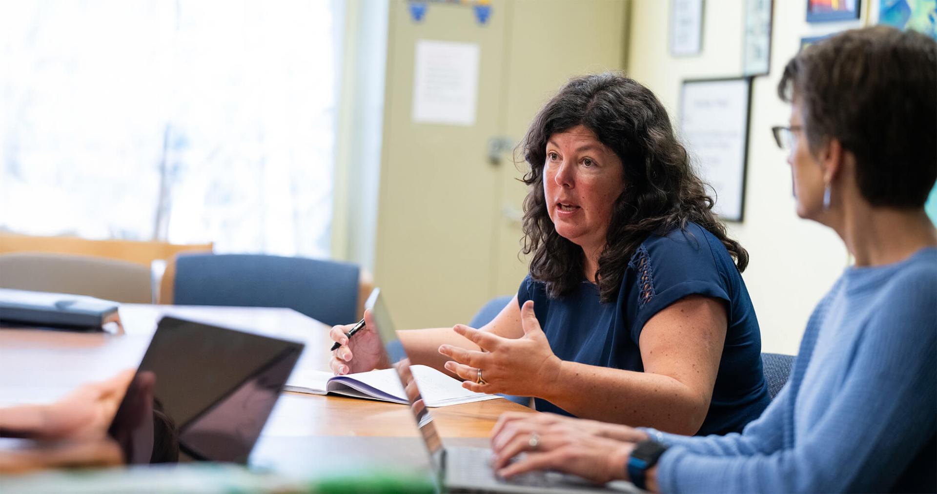 Two faculty members seated at a table in discussion