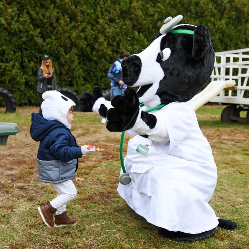 child running into the arms of a person in a cow doctor costume