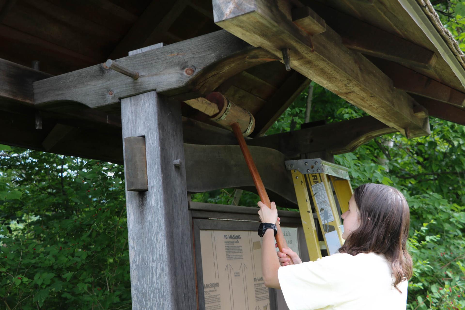 Ella Szczepanski '26 removes the roof pegs from a repurposed trail kiosk in Bethel, VT