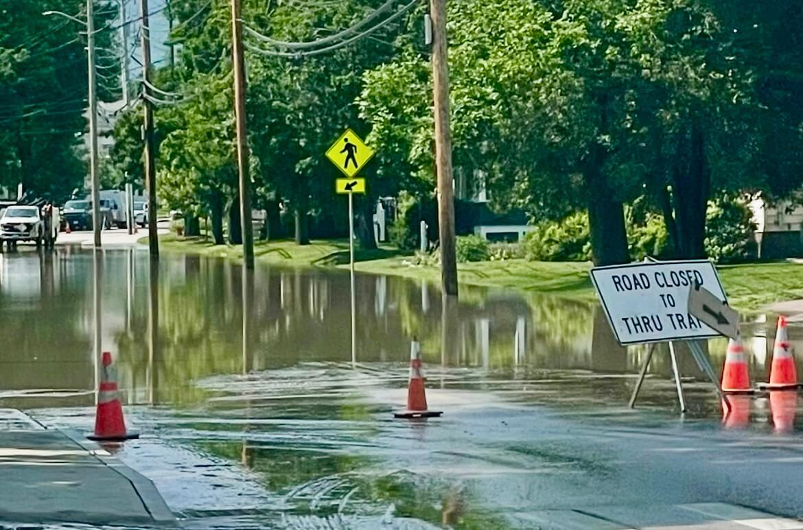 a road closed sign in front of a flooded street