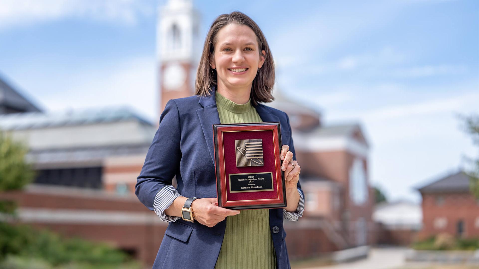 Civil and Environmental Engineering Assistant Professor Kathryn Hinkelman holds her award from the IBPSA