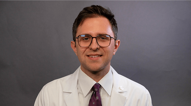 a man in a white coat smiling