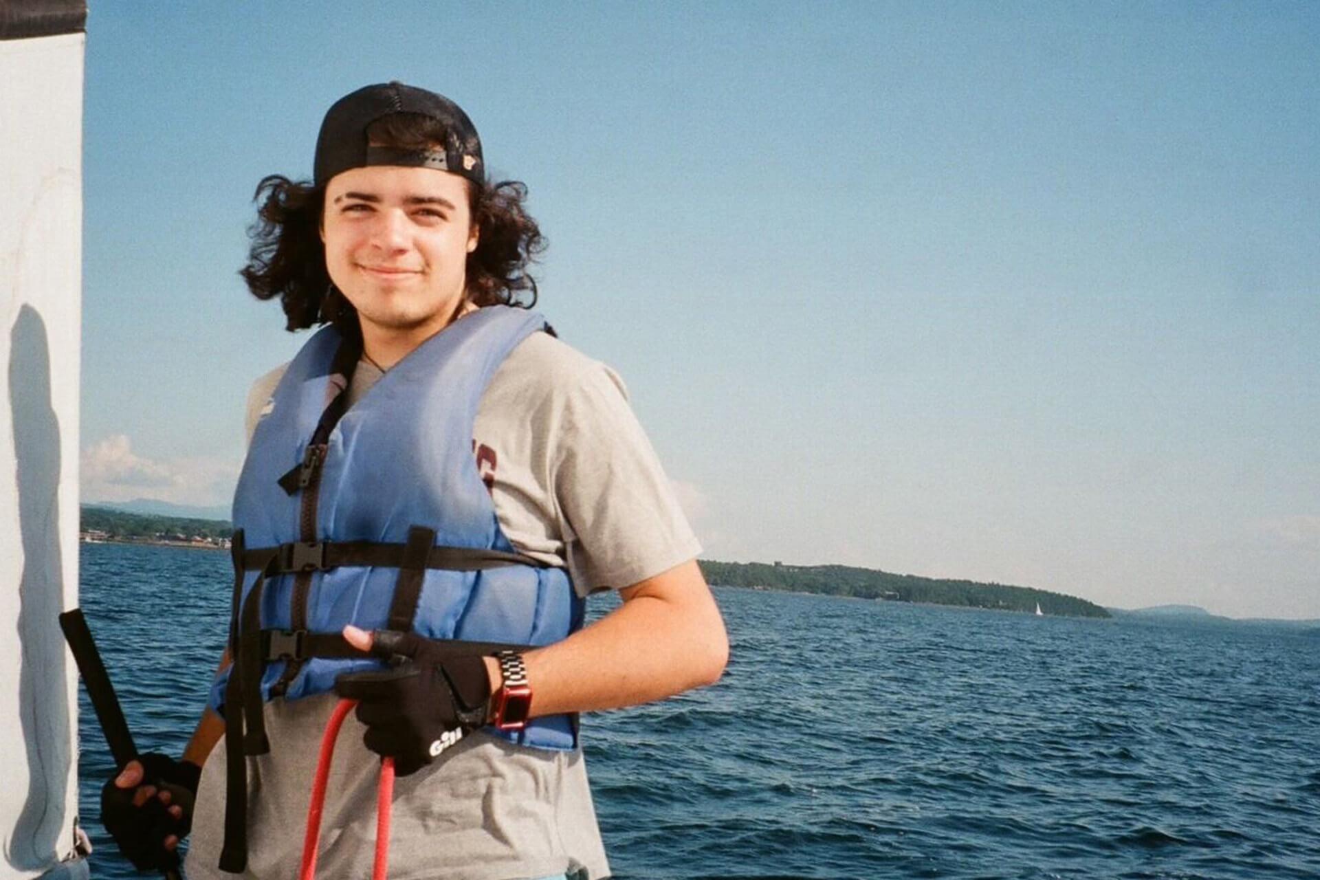 A smiling man in a life jacket on a boat.