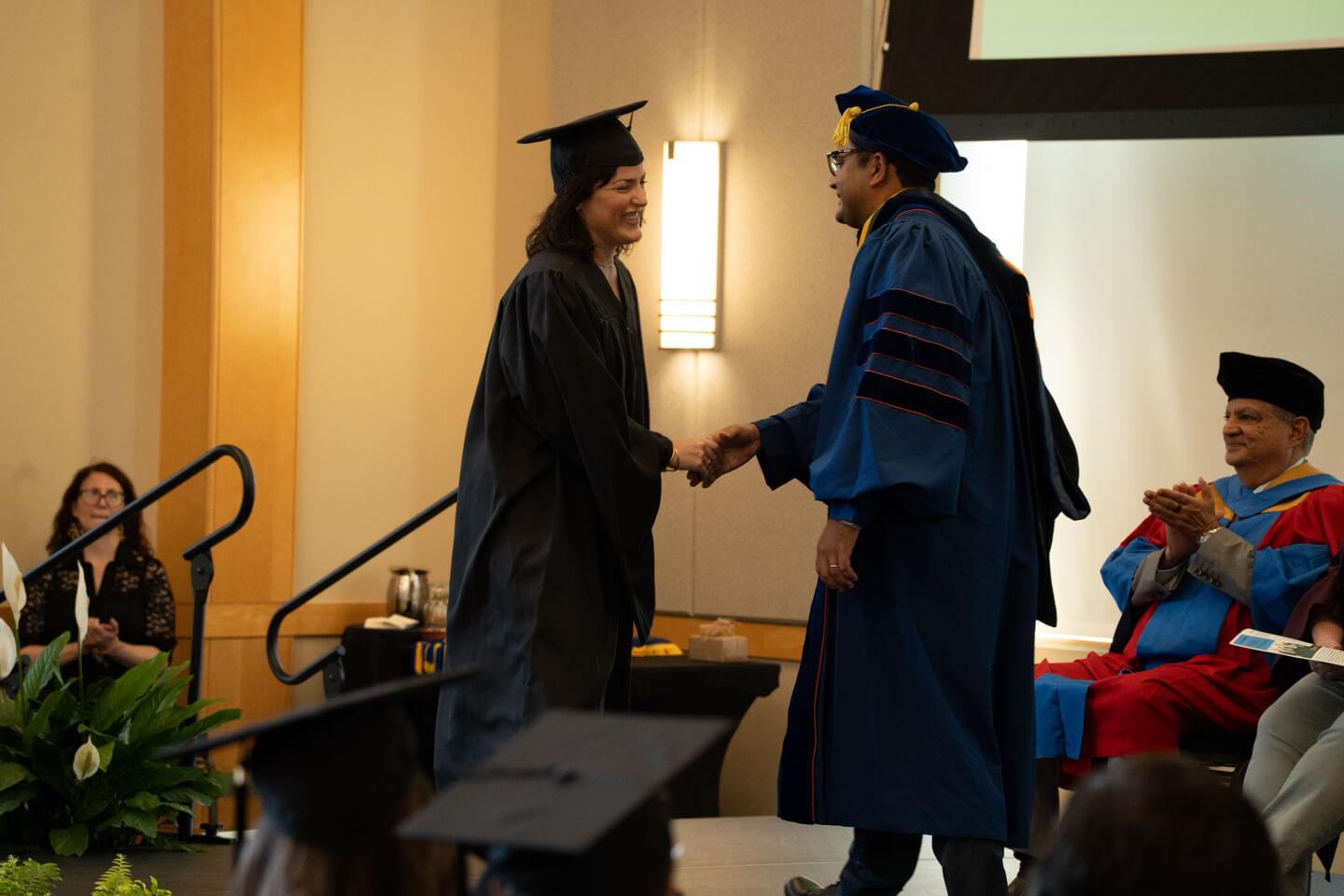 Paige Flanagan shakes hands with program director Srinivas Venugopal