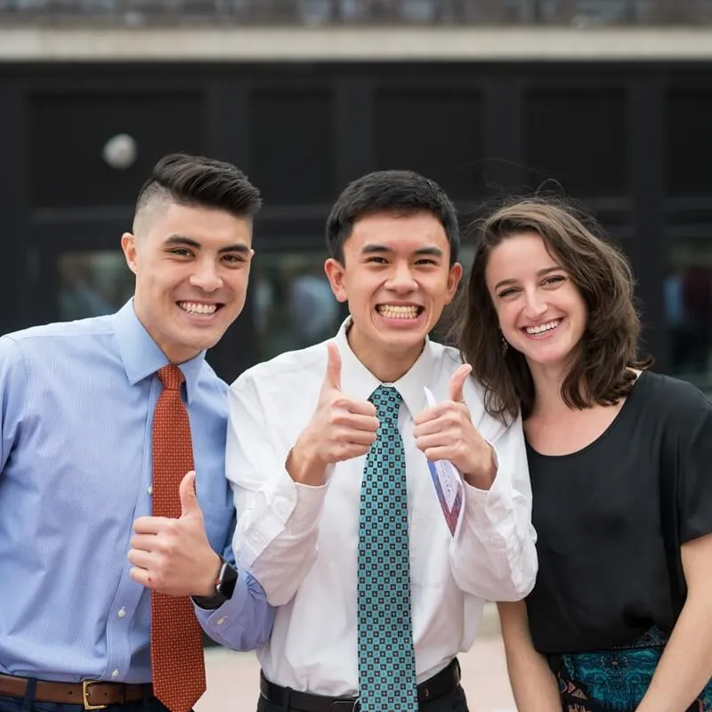 three happy students give the thumbs up