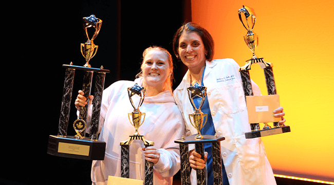 2 people holding trophies
