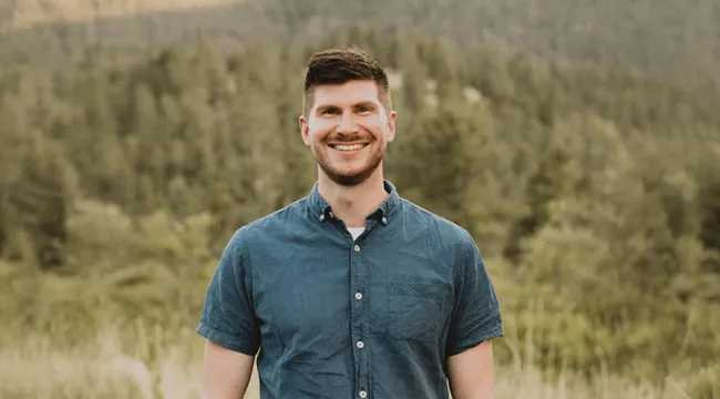 RSENR Alum Brad Koontz standing in front of a blurred mountainous background