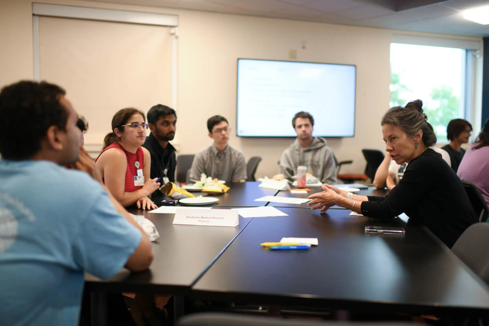 Group of people around a table listening to a person speaking