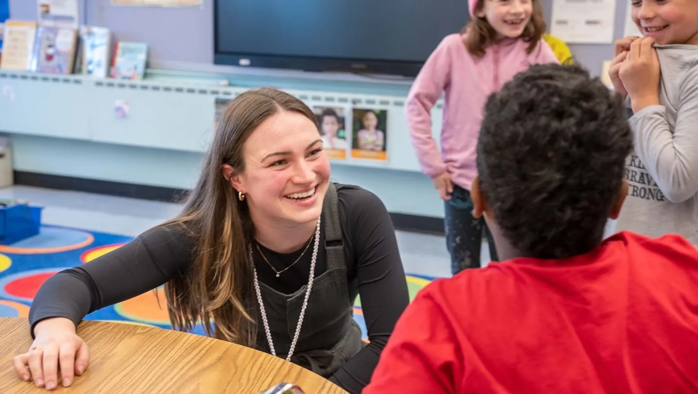 college student engaging elementary school kid in classroom