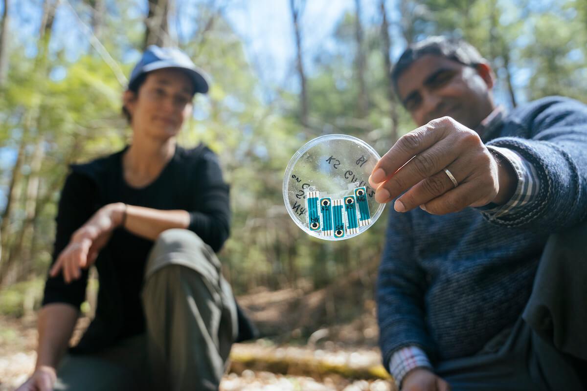 Two people kneeling, one holding a small sensor