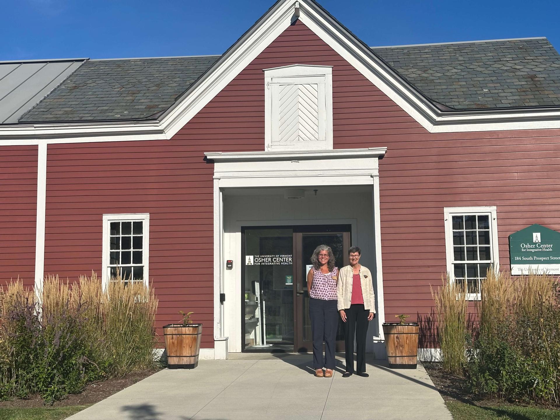 Two people standing in front of UVM's Osher Center building