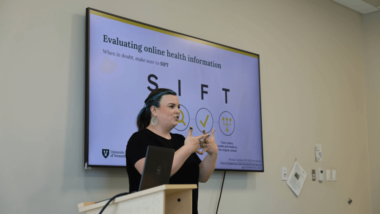 Maria Avery speaks in front of a projector screen that shows a slide detailing the SIFT method.