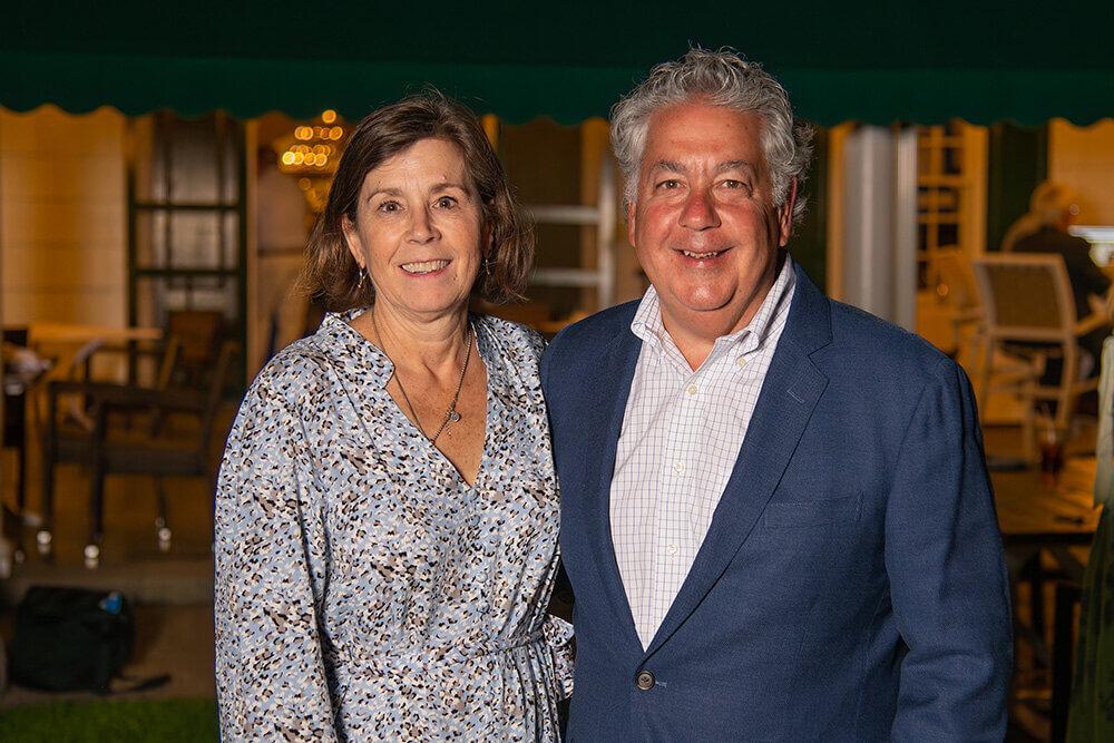 A man and a woman standing outside an outdoor seating area 