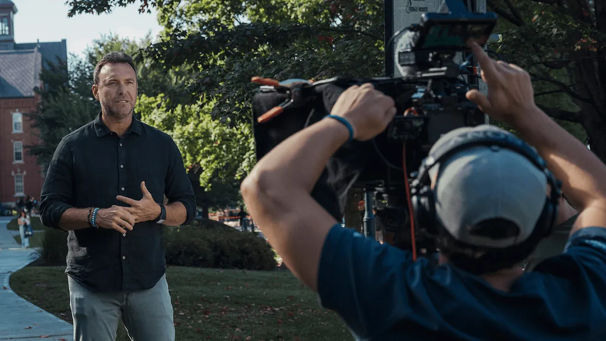A UVM faculty expert being interviewed by journalists in front of Old Mill on UVM's historic campus.