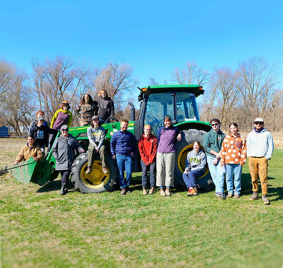 a bunch of people posing in front of a tractor