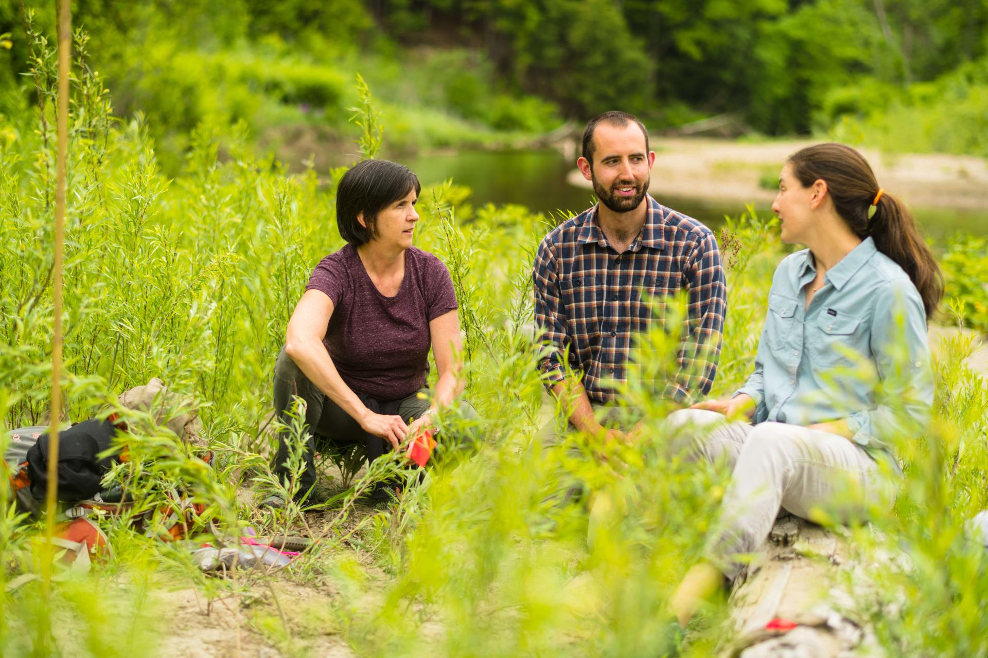 Three people sit in a field. 