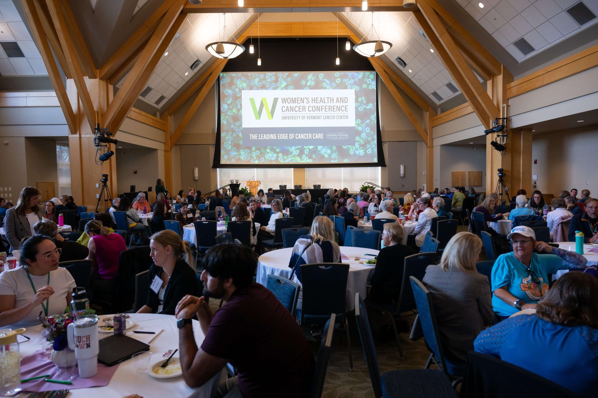 a big room full of people for a conference, with a screen that says Women's Health and Cancer Conference 2025 