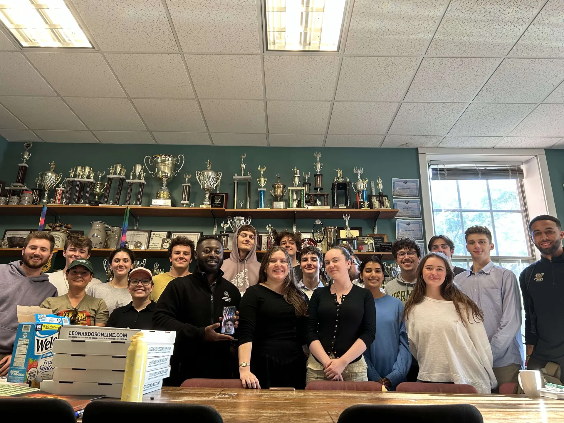 Group of students posing in a trophy-filled room.