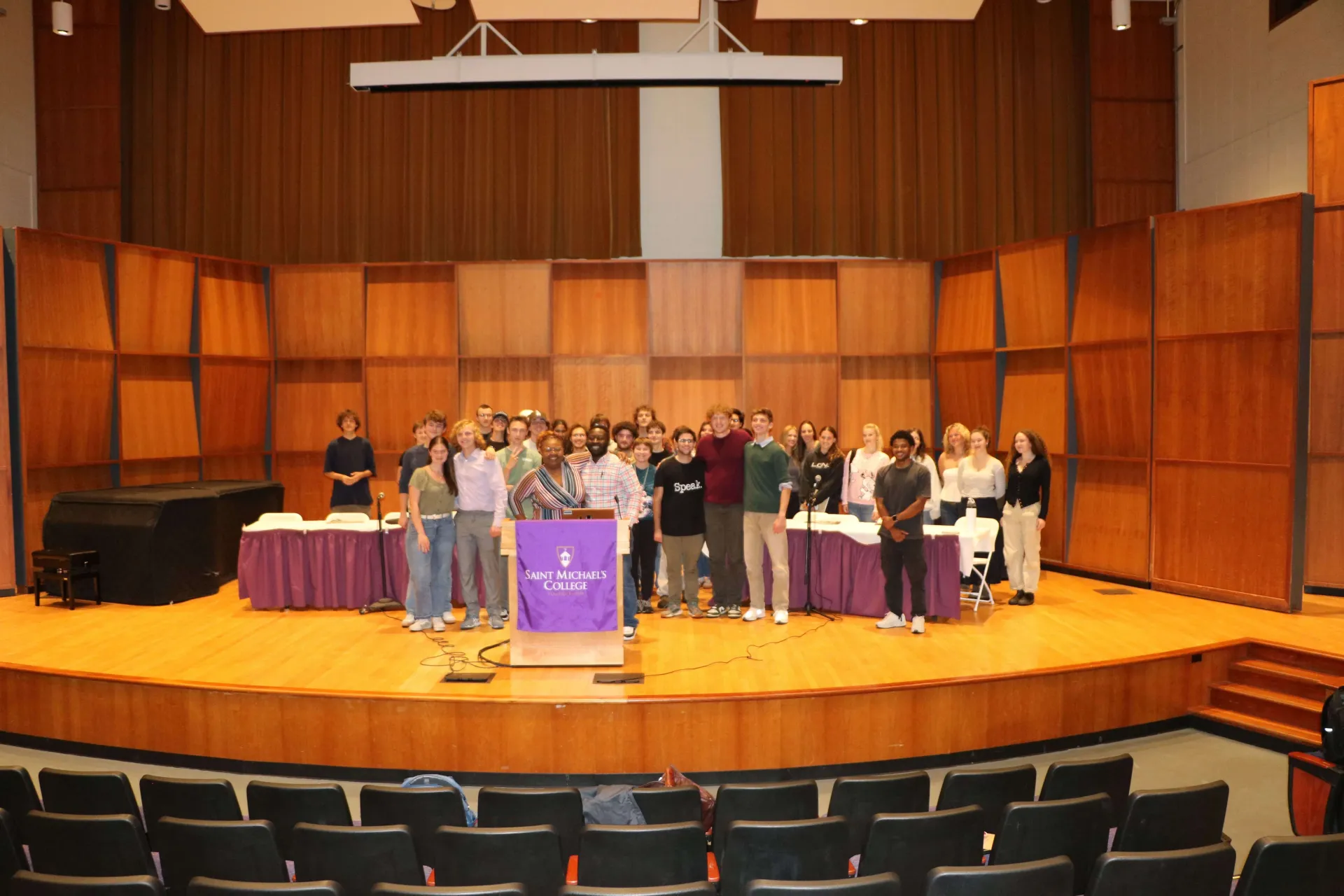 Group photo of students and speakers on stage.