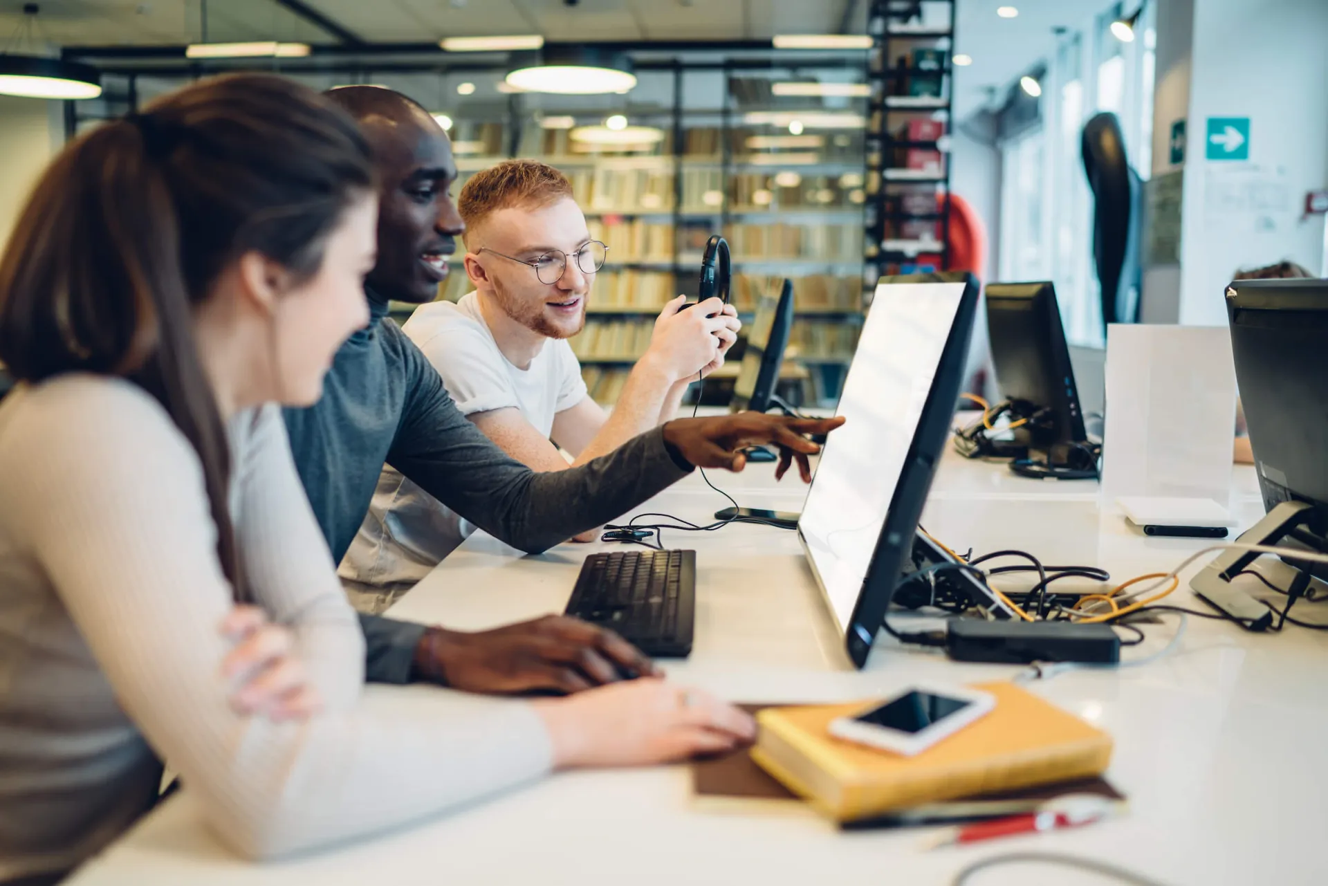 Three students collaborating and pointing at a computer screen
