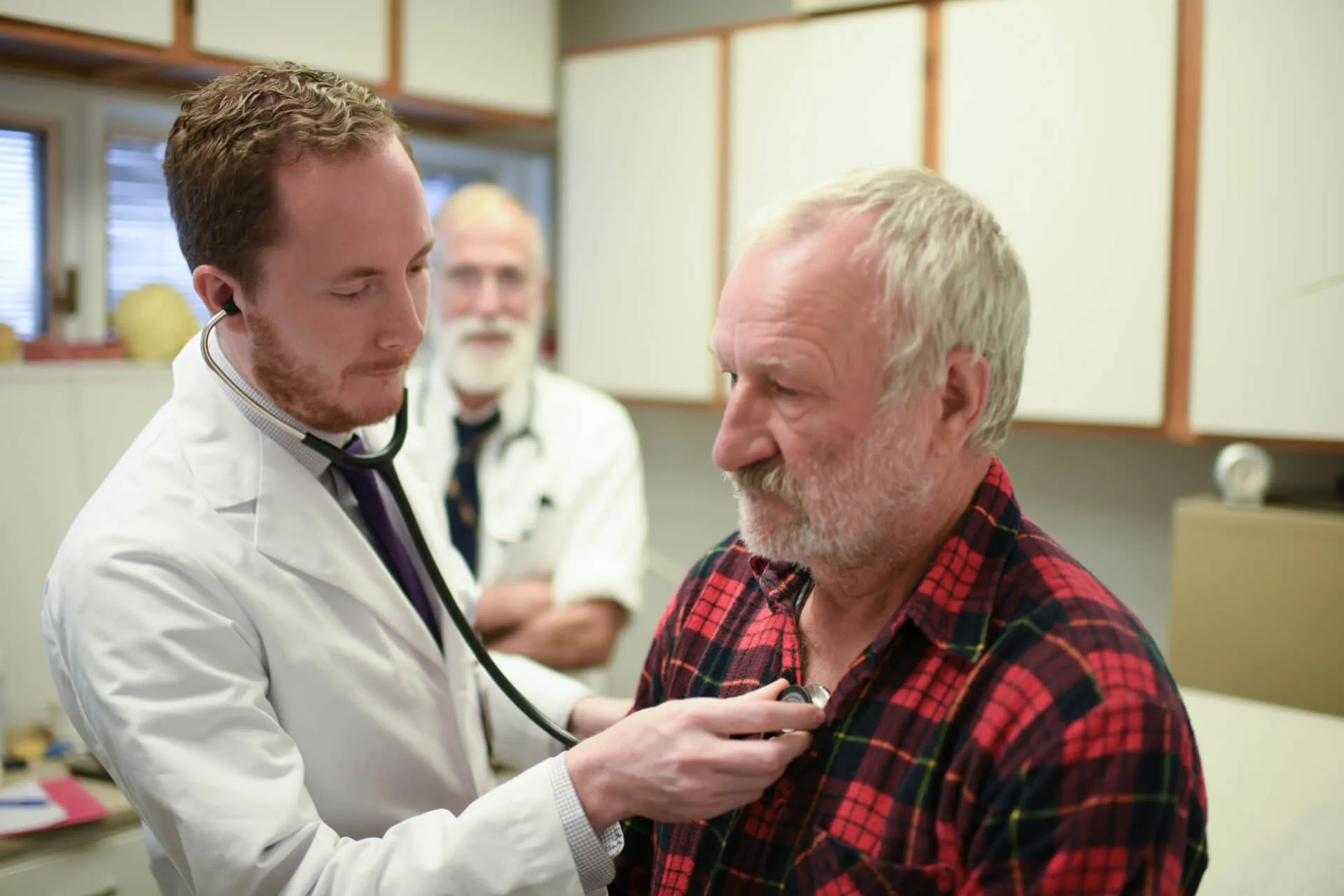 doctor listening to mans heart in an office