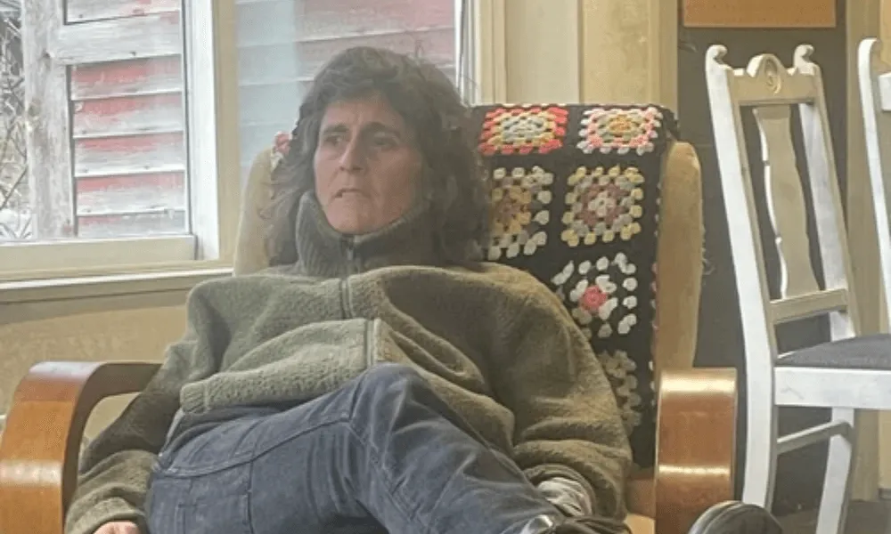 Podcaster Erica Heilman sitting in a chair near a window, wearing a green fleece sweater.