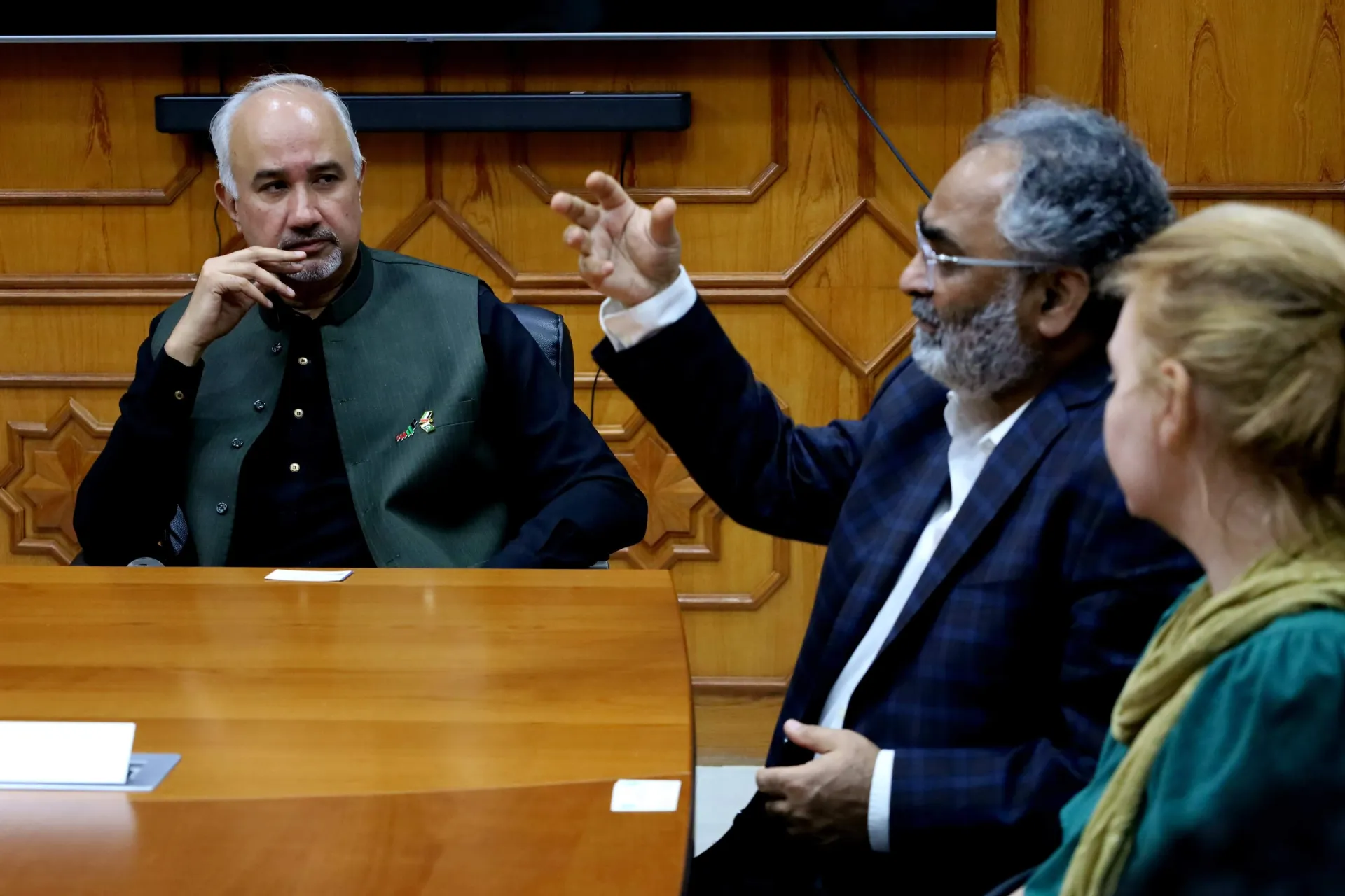 A man speaking to two other people in a formal setting