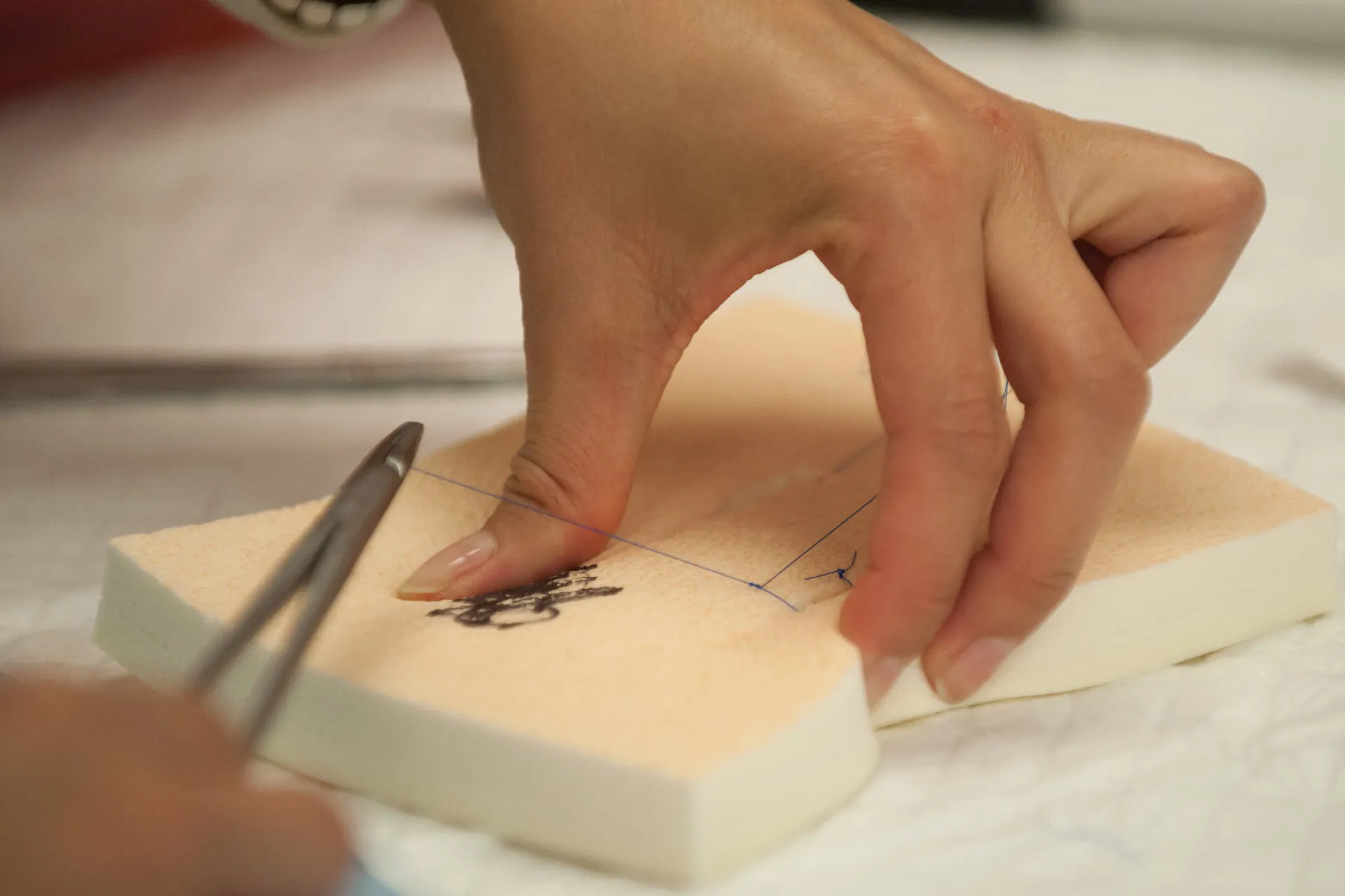 close up of person practicing suturing on foam 