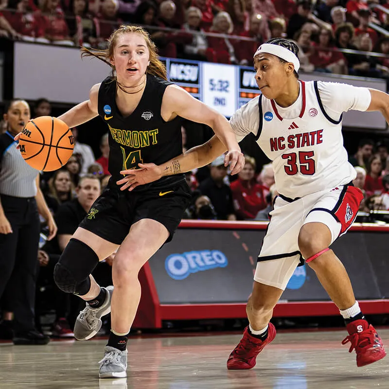 two women's basketball players compete over a basketball on a court