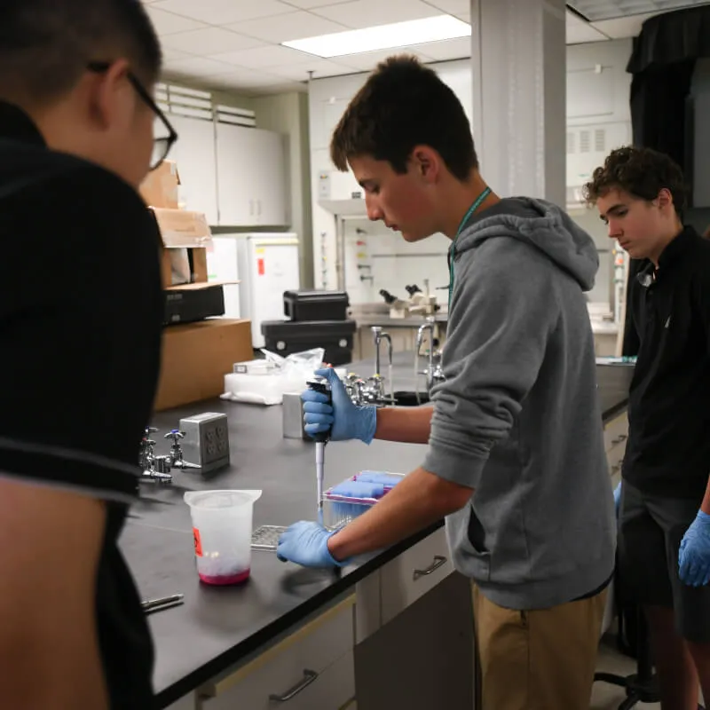 student practices pipetting while two others observe